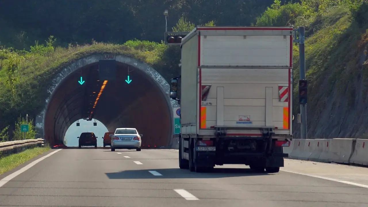 Ciężarówka zbliża się do tunelu. W tunelu widać zielone strzałki, co oznacza, że cemt jest otwarty.