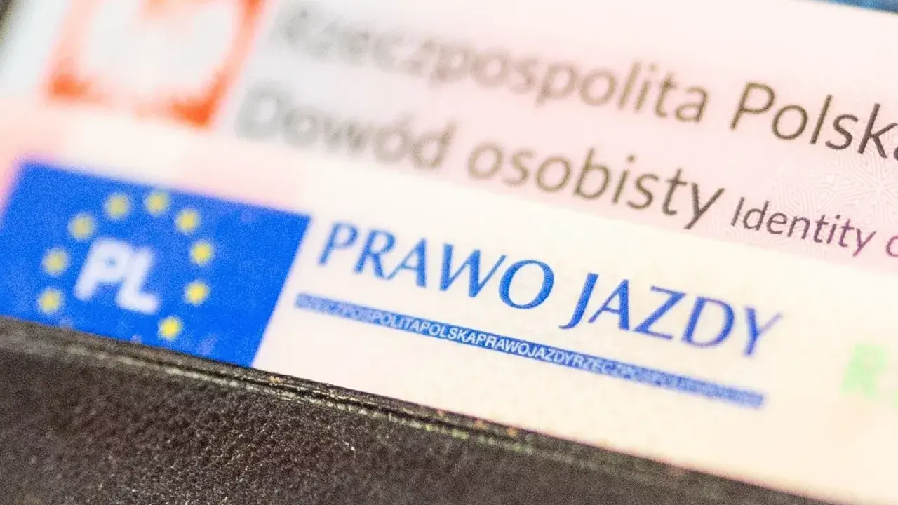 Zbliżenie na polskie dokumenty: dowód osobisty i prawo jazdy. Dokumenty są w portfelu, gotowe do okazania. Prawo jazdy bezterminowe to symbol wolności na drogach.