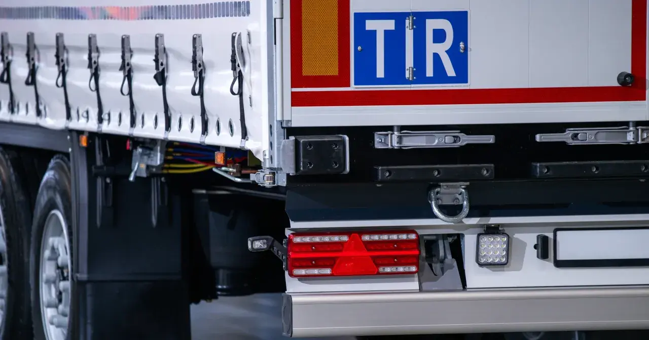 TIR to duża ciężarówka, która przewozi towary. Na zdjęciu widać tył naczepy z charakterystycznym znakiem TIR.