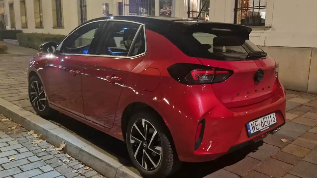 Czerwony samochód firmowy Opel Corsa, zaparkowany na ulicy. Czy to znak zawieszenia działalności?