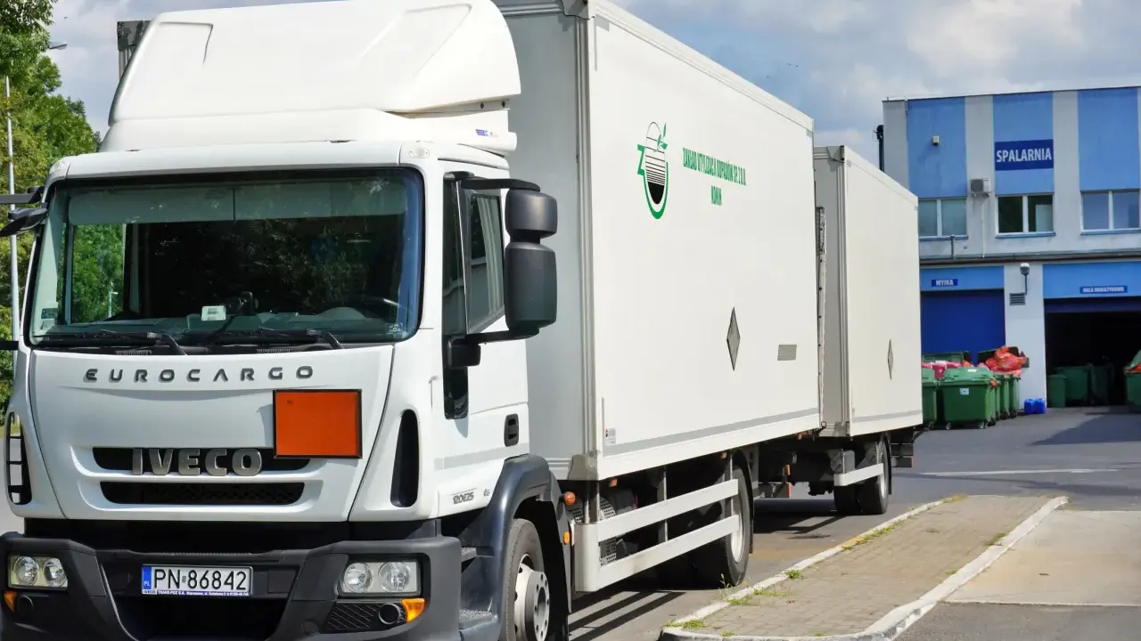 Biała ciężarówka Iveco z naczepą, gotowa do transportu odpadów niebezpiecznych. Na naczepie logo firmy "Zakład Utylizacji Odpadów Sp. z o.o. Konin".