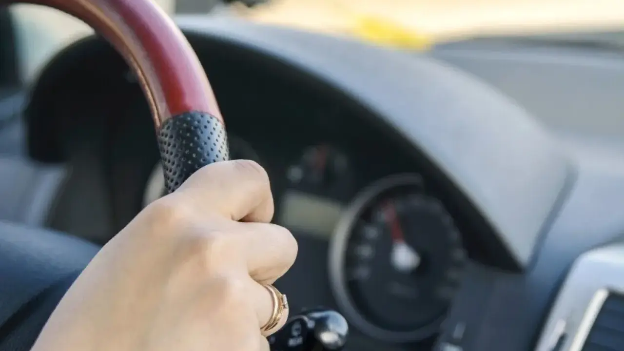 Dłoń na kierownicy, za nią widać prędkościomierz. Długa jazda autostradą może wywołać hipnozę autostradową.