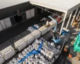 Tabor kolejowy i ciężarówki rozładowują worki z materiałem. To przykład logistyki i transportu.
