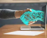 Dłoń wychodząca z laptopa, uścisk dłoni z cyfrową siatką. Ulga na powrót, gdy technologia łączy światy.