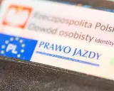 Zbliżenie na polskie dokumenty: dowód osobisty i prawo jazdy. Dokumenty są w portfelu, gotowe do okazania. Prawo jazdy bezterminowe to symbol wolności na drogach.