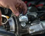 Mechanik sprawdza rozrusznik, który nie kręci. Widoczny jest zębatka i elektromagnes.