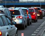 Korki na drodze, typowe dla wakacyjnych wyjazdów. Długi sznur samochodów, czerwone światła stopu.