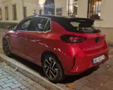 Czerwony samochód firmowy Opel Corsa, zaparkowany na ulicy. Czy to znak zawieszenia działalności?