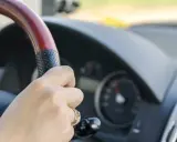 Dłoń na kierownicy, za nią widać prędkościomierz. Długa jazda autostradą może wywołać hipnozę autostradową.