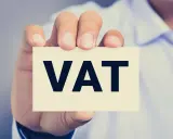 Dłoń trzyma kartkę z napisem VAT. Kluczowe jest zrozumienie proporcji VAT w biznesie.