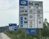Znaki drogowe informują o opłatach i dopuszczalnych predkosci na drodze. Widoczne są ograniczenia prędkości dla różnych pojazdów.