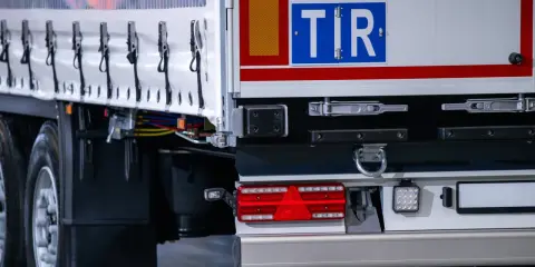TIR to duża ciężarówka, która przewozi towary. Na zdjęciu widać tył naczepy z charakterystycznym znakiem TIR.