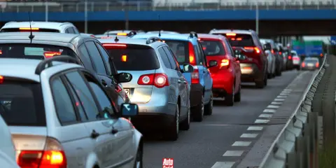 Korki na drodze, typowe dla wakacyjnych wyjazdów. Długi sznur samochodów, czerwone światła stopu.