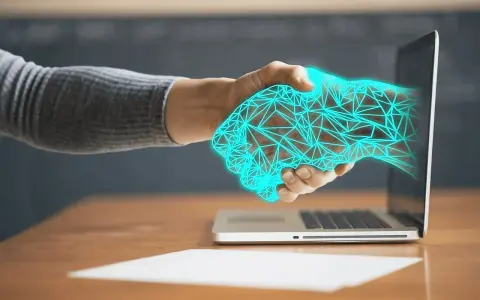 Dłoń wychodząca z laptopa, uścisk dłoni z cyfrową siatką. Ulga na powrót, gdy technologia łączy światy.
