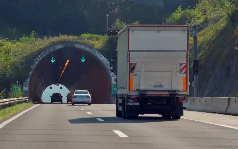 Ciężarówka zbliża się do tunelu. W tunelu widać zielone strzałki, co oznacza, że cemt jest otwarty.
