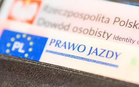Zbliżenie na polskie dokumenty: dowód osobisty i prawo jazdy. Dokumenty są w portfelu, gotowe do okazania. Prawo jazdy bezterminowe to symbol wolności na drogach.