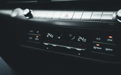 Panel klimatyzacji samochodowej z wyświetlaczem temperatury 24.0. Objawy uszkodzony skraplacz klimatyzacji mogą być trudne do zauważenia na pierwszy rzut oka.