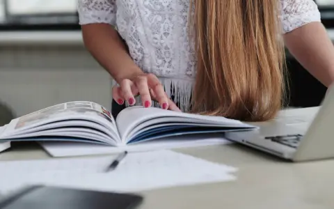 Kobieta przegląda instrukcję wysyłkową wzór, obok leży laptop.