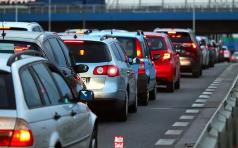 Korki na drodze, typowe dla wakacyjnych wyjazdów. Długi sznur samochodów, czerwone światła stopu.