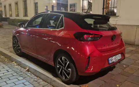 Czerwony samochód firmowy Opel Corsa, zaparkowany na ulicy. Czy to znak zawieszenia działalności?