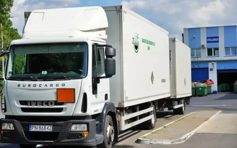 Biała ciężarówka Iveco z naczepą, gotowa do transportu odpadów niebezpiecznych. Na naczepie logo firmy "Zakład Utylizacji Odpadów Sp. z o.o. Konin".