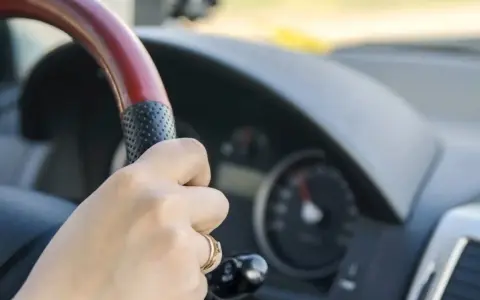 Dłoń na kierownicy, za nią widać prędkościomierz. Długa jazda autostradą może wywołać hipnozę autostradową.