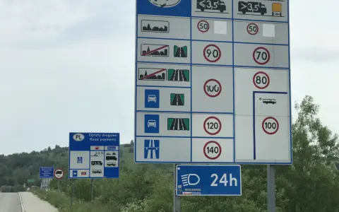Znaki drogowe informują o opłatach i dopuszczalnych predkosci na drodze. Widoczne są ograniczenia prędkości dla różnych pojazdów.
