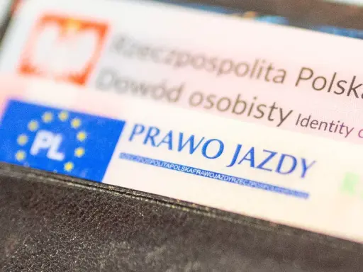 Zbliżenie na polskie dokumenty: dowód osobisty i prawo jazdy. Dokumenty są w portfelu, gotowe do okazania. Prawo jazdy bezterminowe to symbol wolności na drogach.