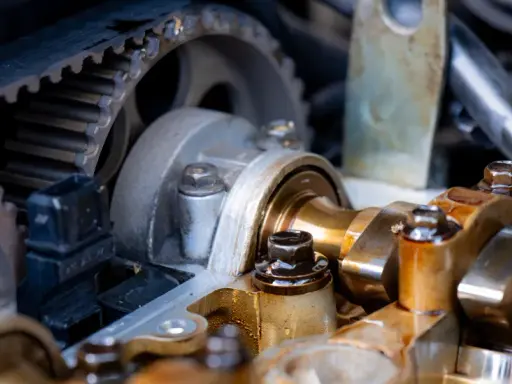 Widok na mechanizm rozrządu silnika samochodowego. Zębatka i pasek rozrządu, elementy wałka rozrządu. Luźny łańcuch rozrządu objawy mogą być groźne.