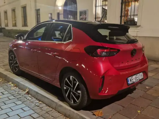 Czerwony samochód firmowy Opel Corsa, zaparkowany na ulicy. Czy to znak zawieszenia działalności?