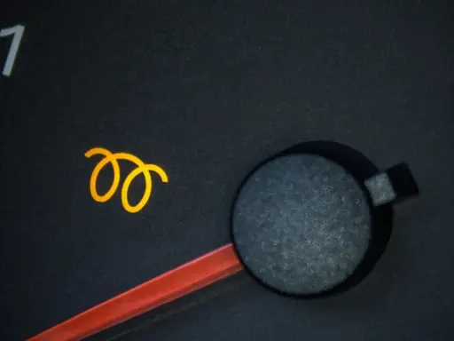Żółta ikona sprężyny na desce rozdzielczej samochodu, sygnalizująca problem z układem żarowym.