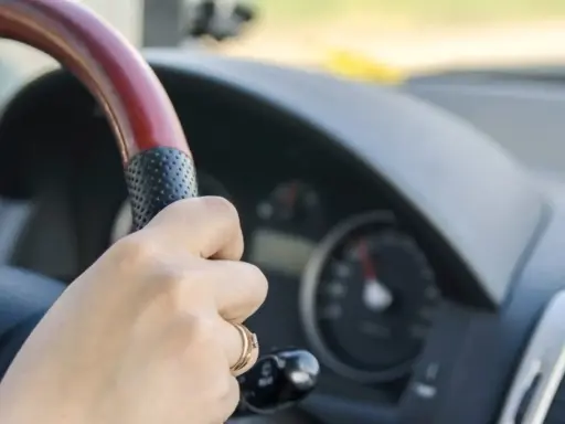Dłoń na kierownicy, za nią widać prędkościomierz. Długa jazda autostradą może wywołać hipnozę autostradową.