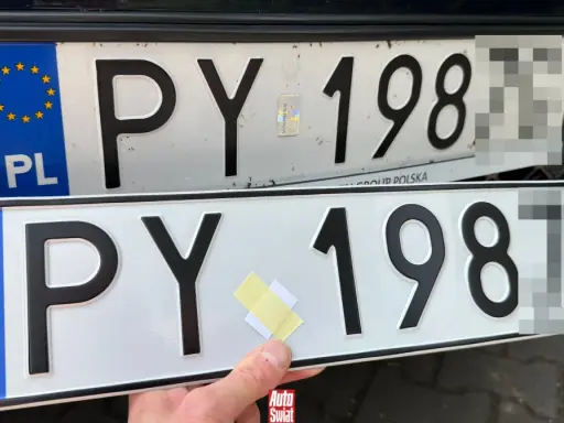 Dwie polskie tablice rejestracyjne, jedna nad drugą. Na górnej widać nalepkę z hologramem. Dolna jest nowa, z taśmą klejącą.