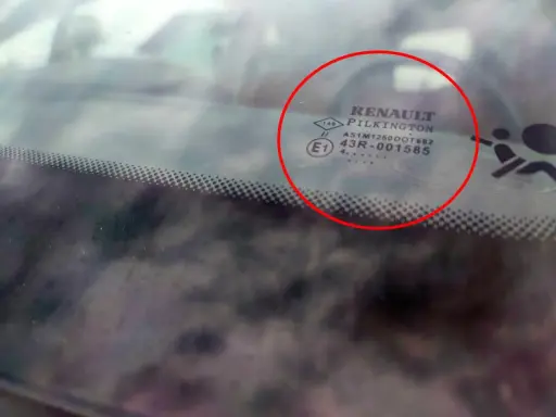 Oznaczenia na szybach samochodowych Renault Pilkington. Widoczne symbole i kody homologacji na przedniej szybie.