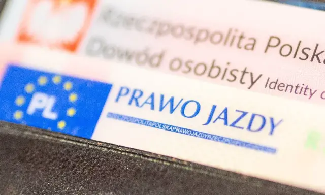 Zbliżenie na polskie dokumenty: dowód osobisty i prawo jazdy. Dokumenty są w portfelu, gotowe do okazania. Prawo jazdy bezterminowe to symbol wolności na drogach.