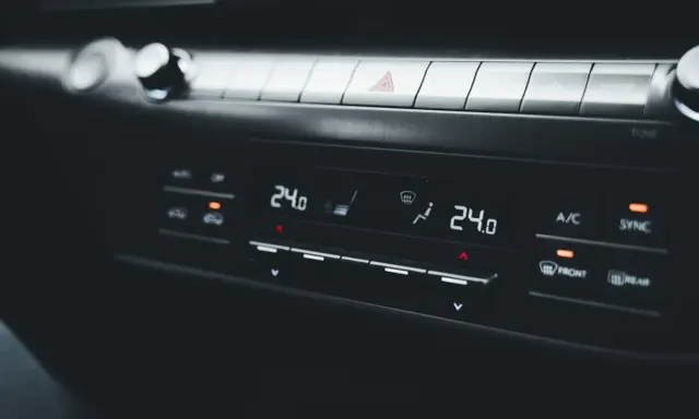 Panel klimatyzacji samochodowej z wyświetlaczem temperatury 24.0. Objawy uszkodzony skraplacz klimatyzacji mogą być trudne do zauważenia na pierwszy rzut oka.