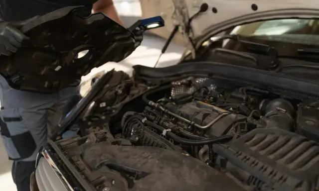 Mechanik sprawdza silnik, który mógł przegrzać się z powodu wysokiej temperatury.