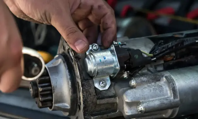 Mechanik sprawdza rozrusznik, który nie kręci. Widoczny jest zębatka i elektromagnes.