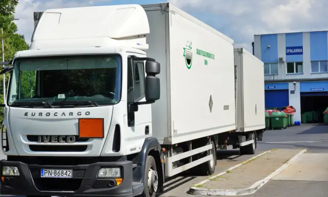 Biała ciężarówka Iveco z naczepą, gotowa do transportu odpadów niebezpiecznych. Na naczepie logo firmy "Zakład Utylizacji Odpadów Sp. z o.o. Konin".