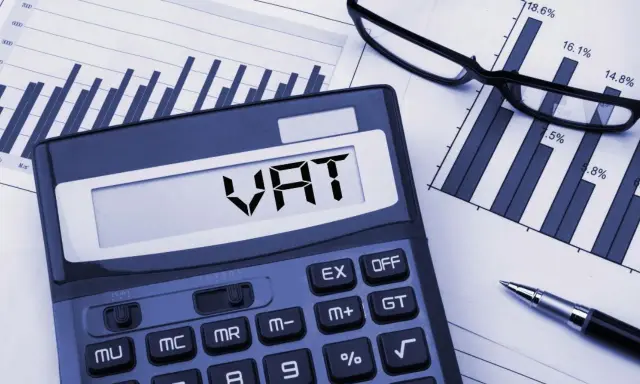 Kalkulator z napisem VAT, wykresy i okulary. Planowanie finansowe i limit vat 2026.