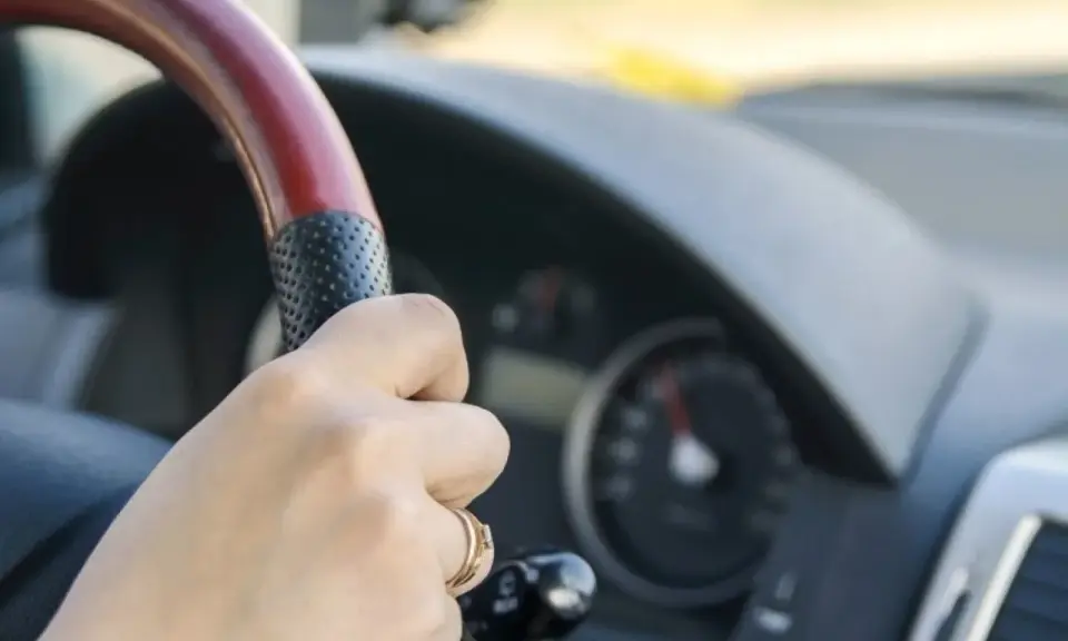 Dłoń na kierownicy, za nią widać prędkościomierz. Długa jazda autostradą może wywołać hipnozę autostradową.