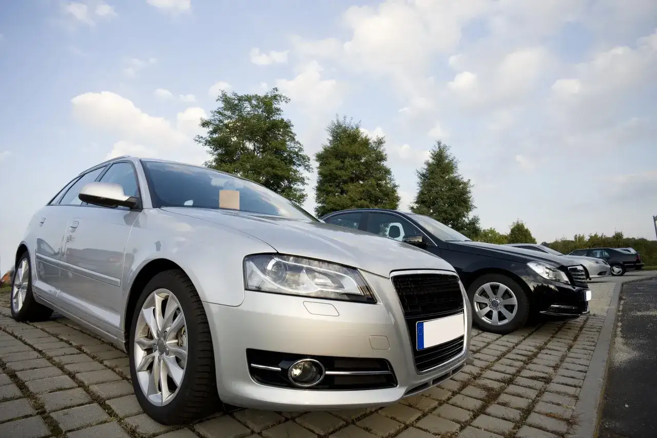 Srebrny i czarny sedan stoją na parkingu. Czy można sprzedać auto bez przeglądu?