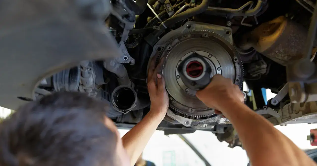 Mechanik sprawdza dwumasę w samochodzie benzynowym. Objawy uszkodzonej dwumasy mogą być niepokojące.