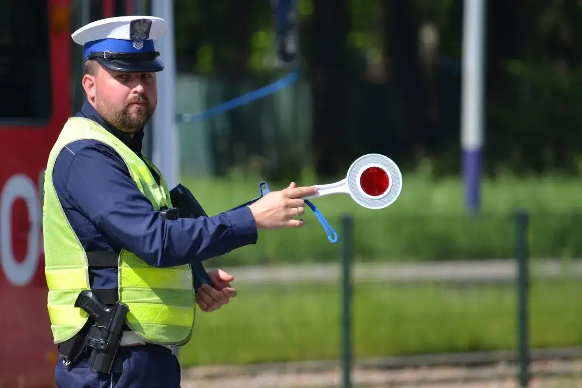 Policjant w kamizelce odblaskowej trzyma lizak do zatrzymywania pojazd&oacute;w. Uważaj, bo za wykroczenie możesz dostać 15 punkt&oacute;w karnych.