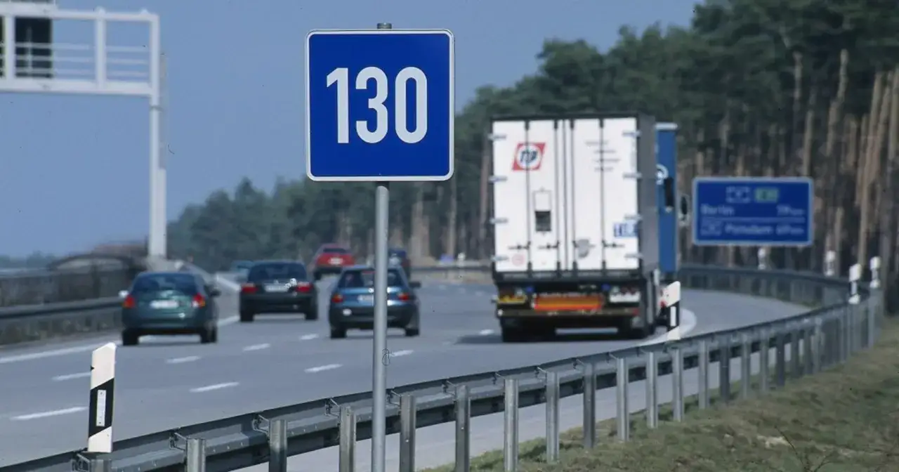 Znak ograniczenia prędkości 130 km/h na autostradzie w Niemczech. W tle ciężar&oacute;wka i samochody.