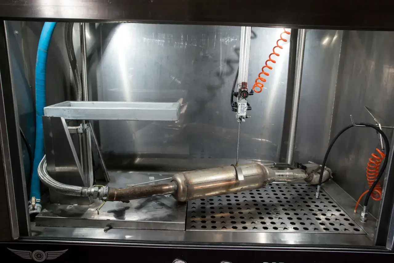 Urządzenie do czyszczenia DPF, zapobiegające częstemu wypalaniu DPF. Metalowa komora z elementami układu wydechowego.