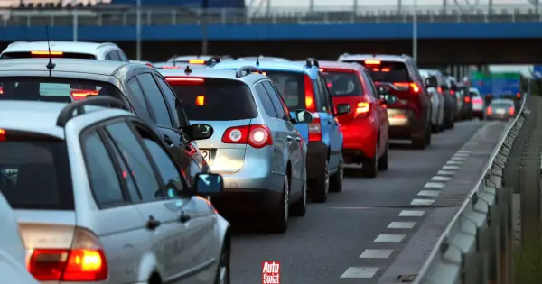 Korki na drodze, typowe dla wakacyjnych wyjazdów. Długi sznur samochodów, czerwone światła stopu.