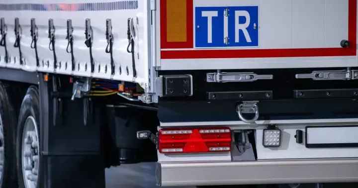 TIR to duża ciężarówka, która przewozi towary. Na zdjęciu widać tył naczepy z charakterystycznym znakiem TIR.